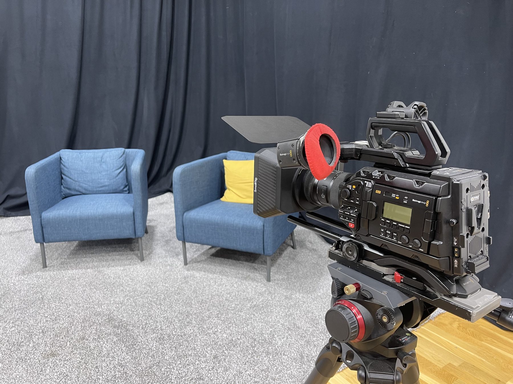 Blackmagic cinema camera with matte box rigged on a tripod facing the interview set