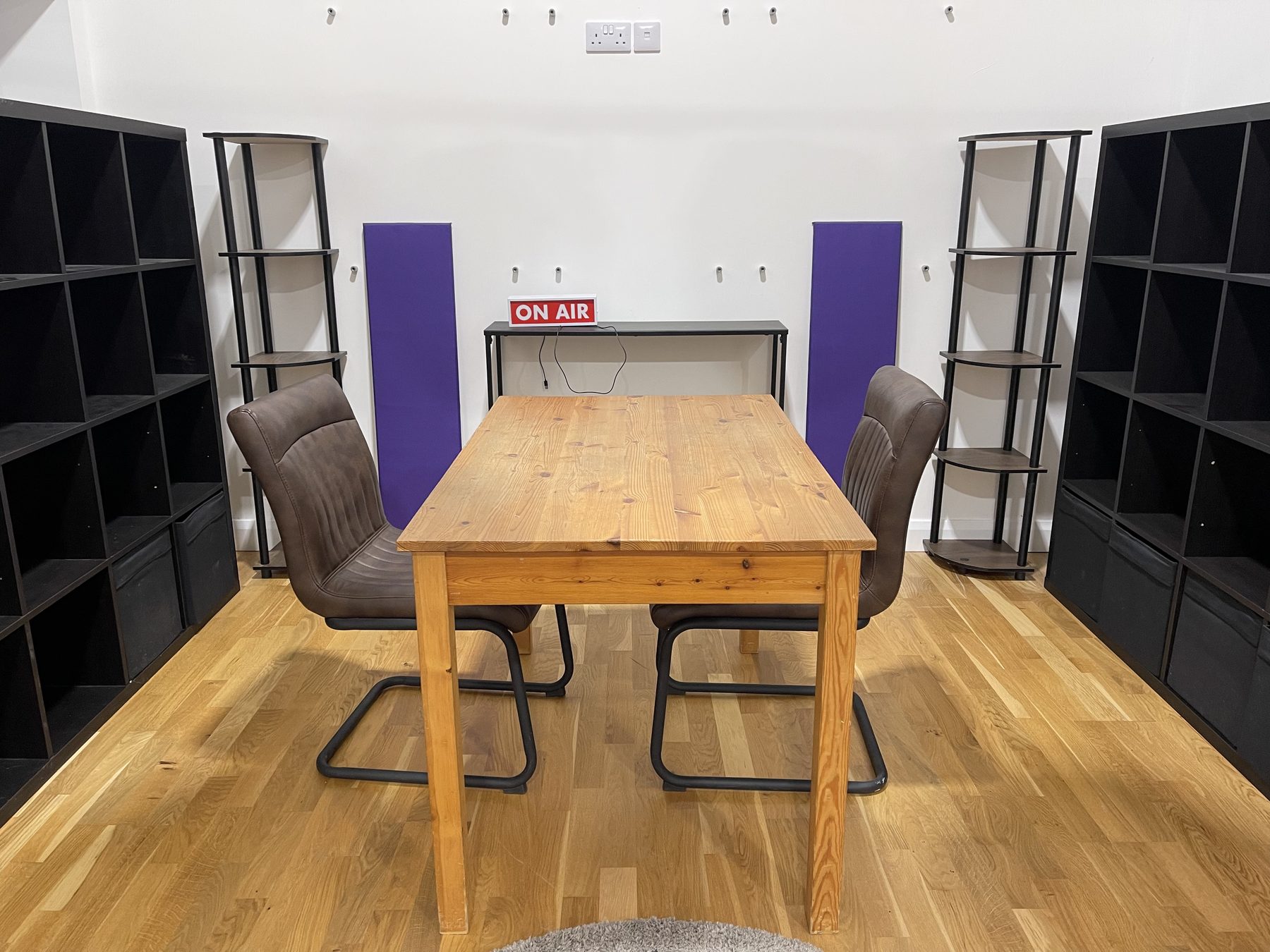 Podcast table and chairs set up beneath an On Air sign in Studio Two